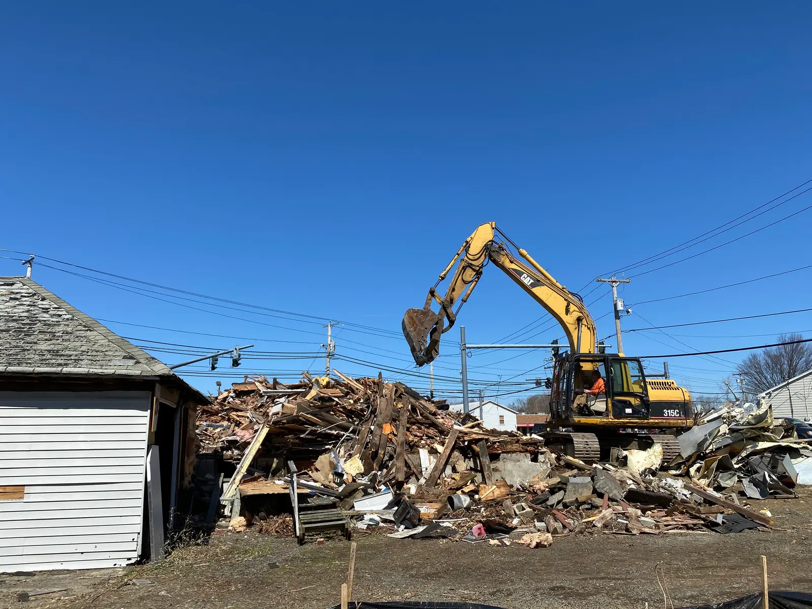 Excavator working the debris pile during a Milford CT demolition project